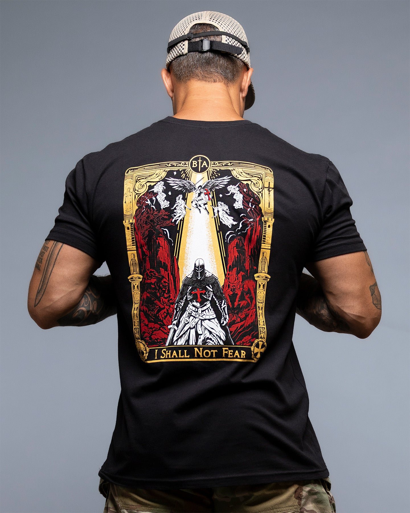 Man wearing a black t-shirt with a graphic design on the back, standing against a gray background. #color_black