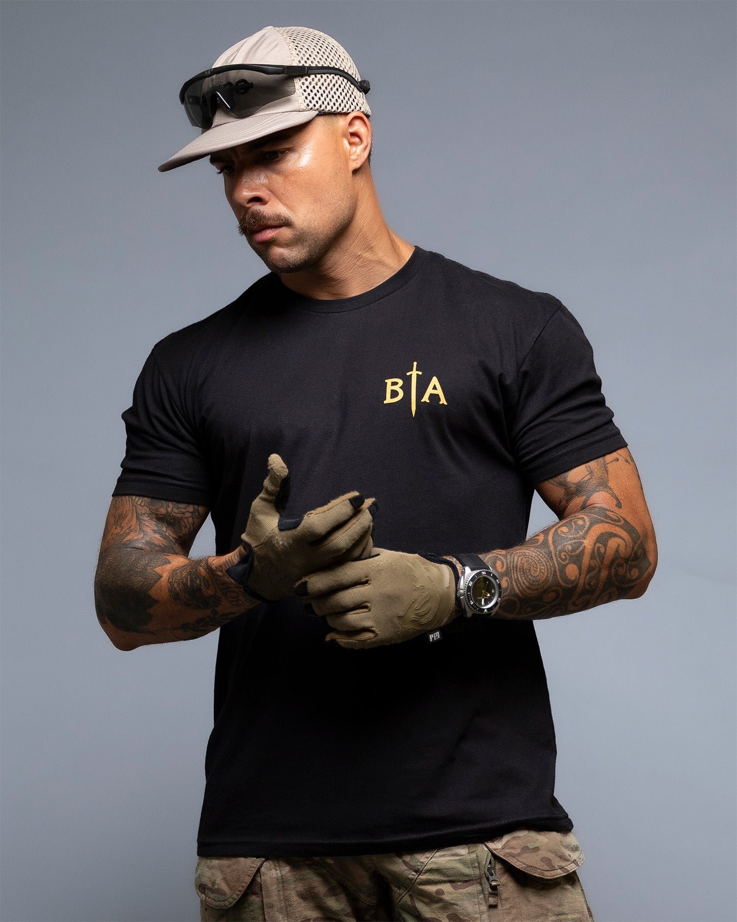 Man wearing a black t-shirt with 'BIA' logo, cap, and gloves on a gray background. #color_black